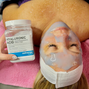 A woman laying on a table wearing a hydration mask. The container for the mask is next to her.