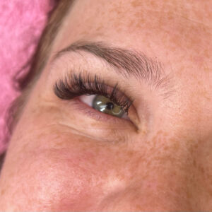 A woman's eyelash after receiving a hybrid lash fill in. Her eyelashes are very dark and full.