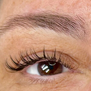 A woman's eye with a classic lash fill in. Her eyelashes are long, dark and sharply defined.