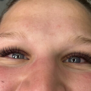 A woman's eyes showing off a full set of hybrid lashes. Her eyelashes look very full and dark.