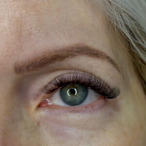 A woman's eye with a volume fill-in lash treatment. This treatment makes eyelashes thicker and fuller.